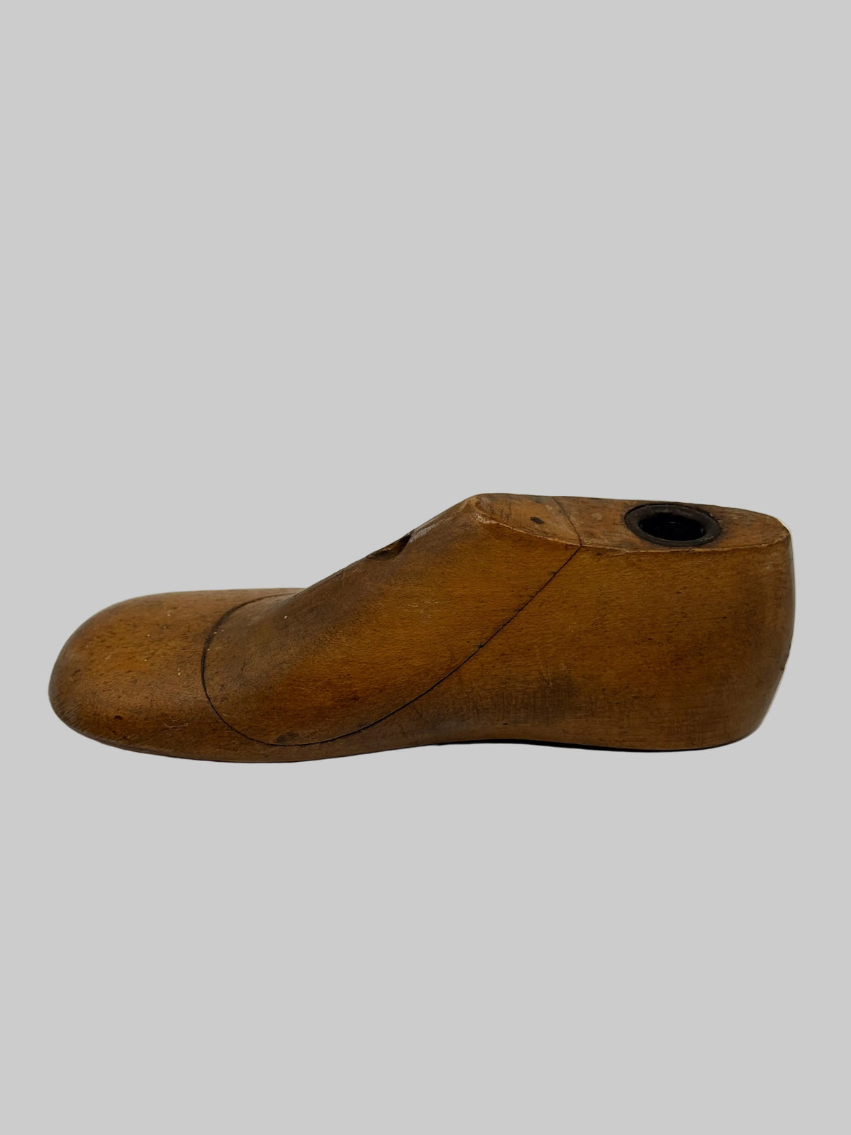 A vintage wooden shoe tree with a curved shape and a circular opening at the back, shown on a plain white background.