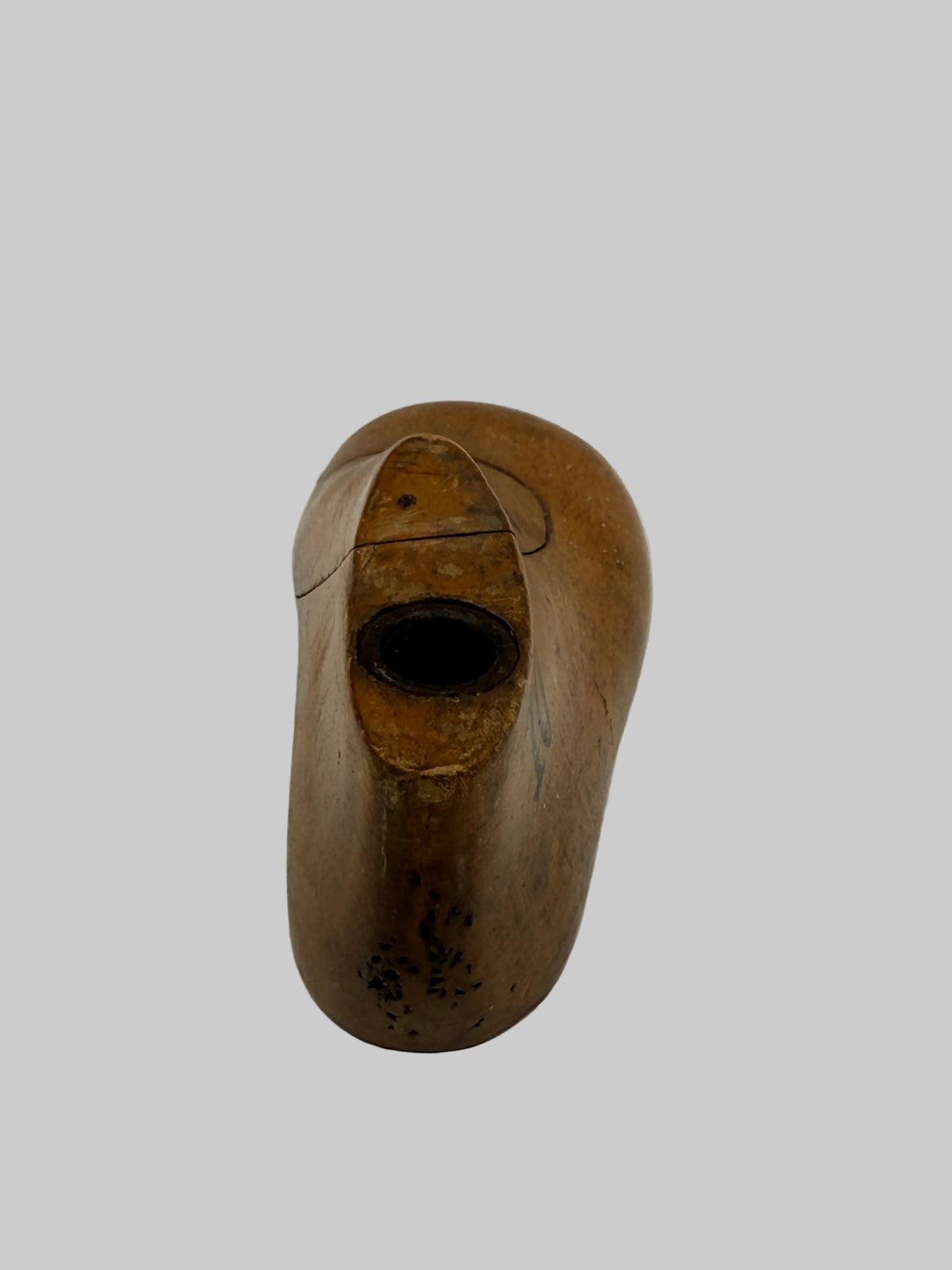 A single carved wooden object with a rounded organic shape and a dark oval opening on top, photographed on a plain light background.